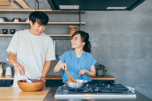 男女が笑顔で料理をしている写真